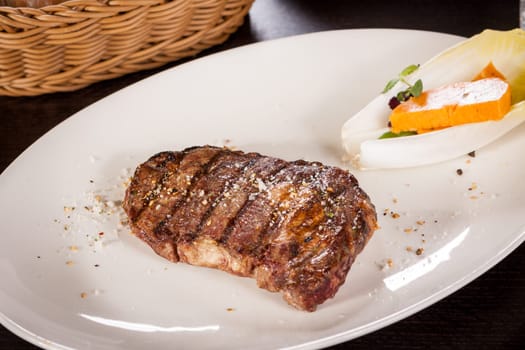 Succulent grilled beef fillet steak with homemade herb butter on a plate isolated against a white background
