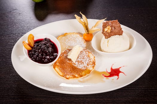 Delicious sweet pancakes as desser with vanilla ice cream prepared on a white plate