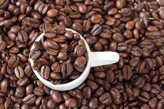 Espresso cup stands between many coffee beans