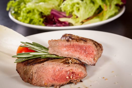 Medium fried beef steak fillet with pepper and rosemary sliced on a plate
