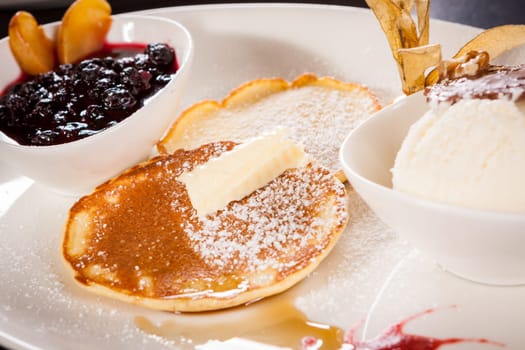 Delicious sweet pancakes as desser with vanilla ice cream prepared on a white plate