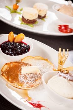 Delicious sweet pancakes as desser with vanilla ice cream prepared on a white plate