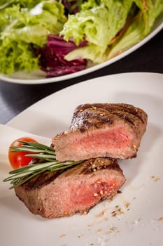 Medium fried beef steak fillet with pepper and rosemary sliced on a plate