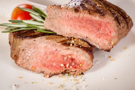 Medium fried beef steak fillet with pepper and rosemary sliced on a plate