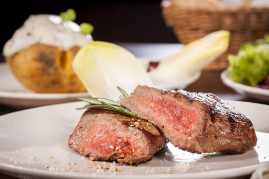 Medium fried beef steak fillet with pepper and rosemary sliced on a plate