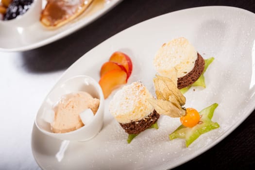 Brownie chocolate brownie with ice cream and plums prepared on a plate