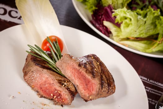 Medium fried beef steak fillet with pepper and rosemary sliced on a plate
