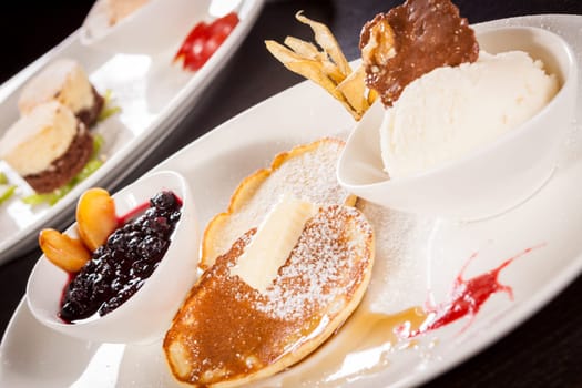 Delicious sweet pancakes as desser with vanilla ice cream prepared on a white plate