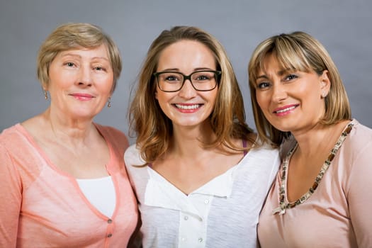 three generations grandmother mother and daughter in portrait against grey background family