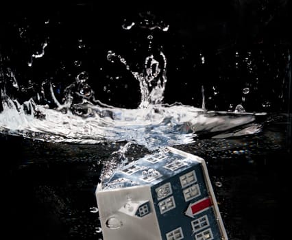 Toy house sinking underwater on a black background