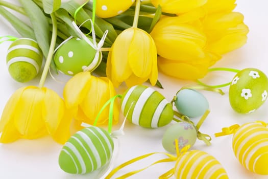 Colourful yellow tulips with green leaves and Easter eggs for Easter Mother's Day Valentine's Day isolated on white background