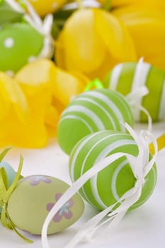 Colourful yellow tulips with green leaves and Easter eggs for Easter Mother's Day Valentine's Day isolated on white background