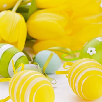 Colourful yellow tulips with green leaves and Easter eggs for Easter Mother's Day Valentine's Day isolated on white background