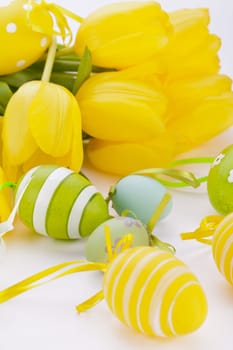 Colourful yellow tulips with green leaves and Easter eggs for Easter Mother's Day Valentine's Day isolated on white background