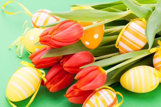 Colourful yellow and red Tulip with Easter eggs decorated at Easter with text space on green background