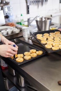 chef solves freshly baked tarts from the mould in the kitchen restaurant pastry shop
