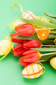 Colourful yellow and red Tulip with Easter eggs decorated at Easter with text space on green background