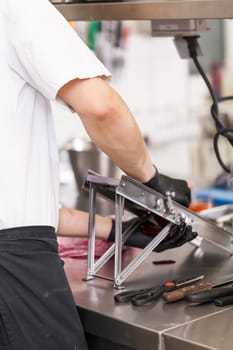 cook rubs fresh red beetroot on rub with gloves to protect against stains in the restaurant kitchen preparation eat