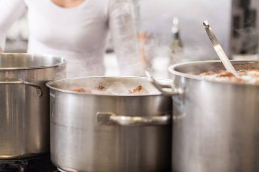 gastronomy restaurant kitchen with hob and steaming pots while cooking to prepare dinner dinner
