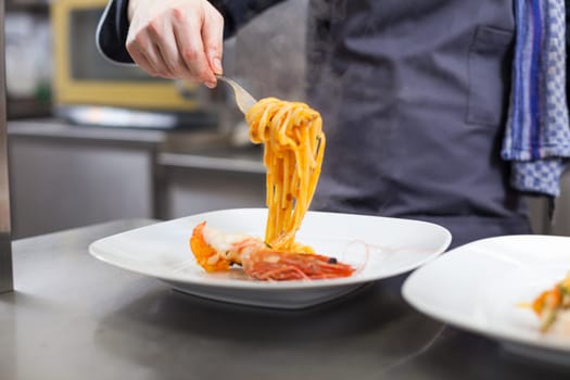 chef prepares fresh pasta spaghetti with shrimp crusts on a plate at the restaurant