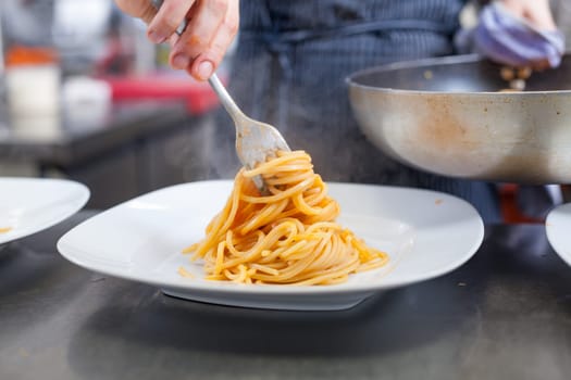 chef prepares fresh pasta spaghetti with shrimp crusts on a plate at the restaurant
