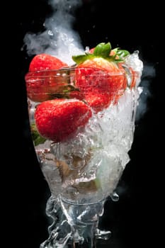 Fruit cocktail glass with steam and smoke, and water movement frozen, all on a black background