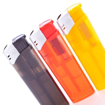 Series of different coloured lighters with electric piezo ignition insulated against white background