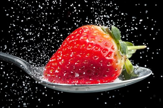 Strawberry on a spoon with sugar pouring over it, frozen with high speed photography