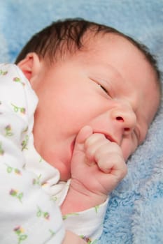 Newborn baby boy portrait while learning to suck on his fist