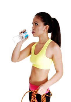 A young slim Chinese woman in an exercise bra standing for white.background drinking water from a bottle..