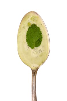 Green soup of peas with mint on a spoon