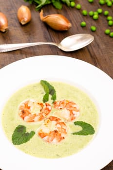 Pea cream soup with shrimp and mint in portrait format