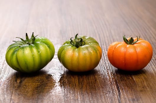 Green and red tomatoes on a wooden table