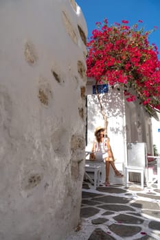 Woman in hat and white dress sitting under bougainvillea