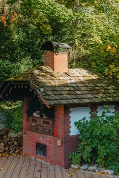 An Old Stove And Firewood For It In The Yard In The Village. Old Stone Fireplace Outdoors In The Fall. Traditional Brick Oven With Wood For Baking Bread Outdoor In Europe.