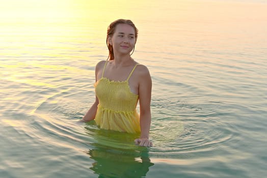 Young female traveler posing on the beach by the sea at sunrise and sharing her adventure travel.