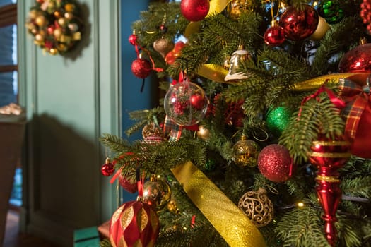 Stylish Christmas minimalist interior. Comfort home with fireplace. Gifts boxes under Christmas tree with decorations red balls in white living room.