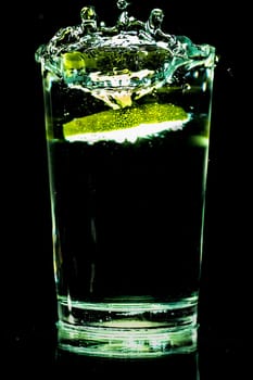 A glass of cold water with slices of lemon making a splash