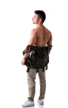 Muscular young man with military taking off vest on naked torso, full body shot from the back