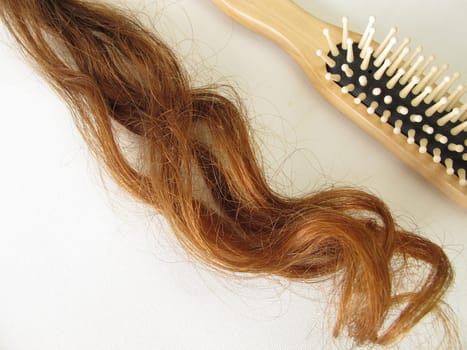 Real maroon hair strands and a hairbrush