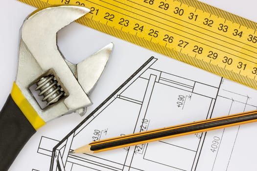 Wrench, ruler and pencil on the building blueprints