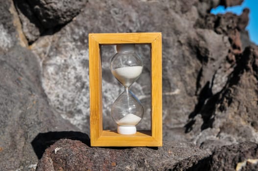 Time Concept White Sand Hourglass on the Volcanic Rocks
