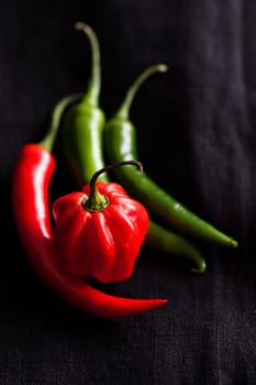 Closeup of red and green chili peppers on dark background
