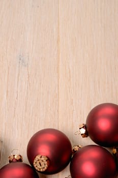 Red Christmas baubles on a wooden background with space for your text