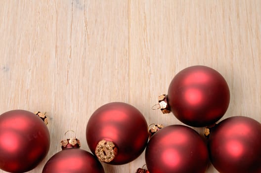 Red Christmas baubles on a wooden background with space for your text