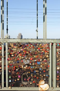 Cologne,Germany – February 02,2014: Love locks,chains and hearts on the fence of the Hohenzollern Bridge with office buildings in the background on February 2,2014 in Cologne.