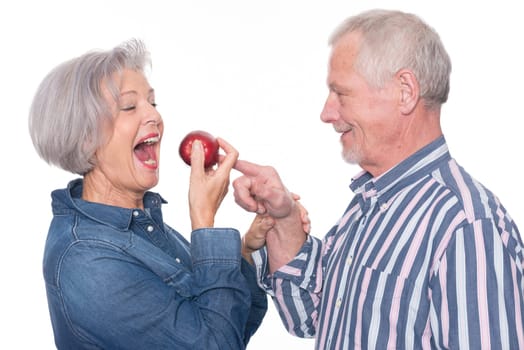 Senior couple with an apple against a white background