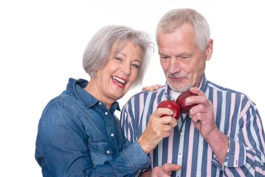 Senior couple with an apple against a white background