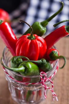 Closeup of red and green chili peppers in glass with decorative string