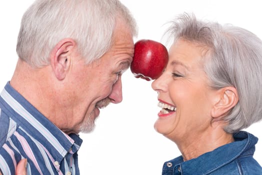Senior couple with an apple against a white background